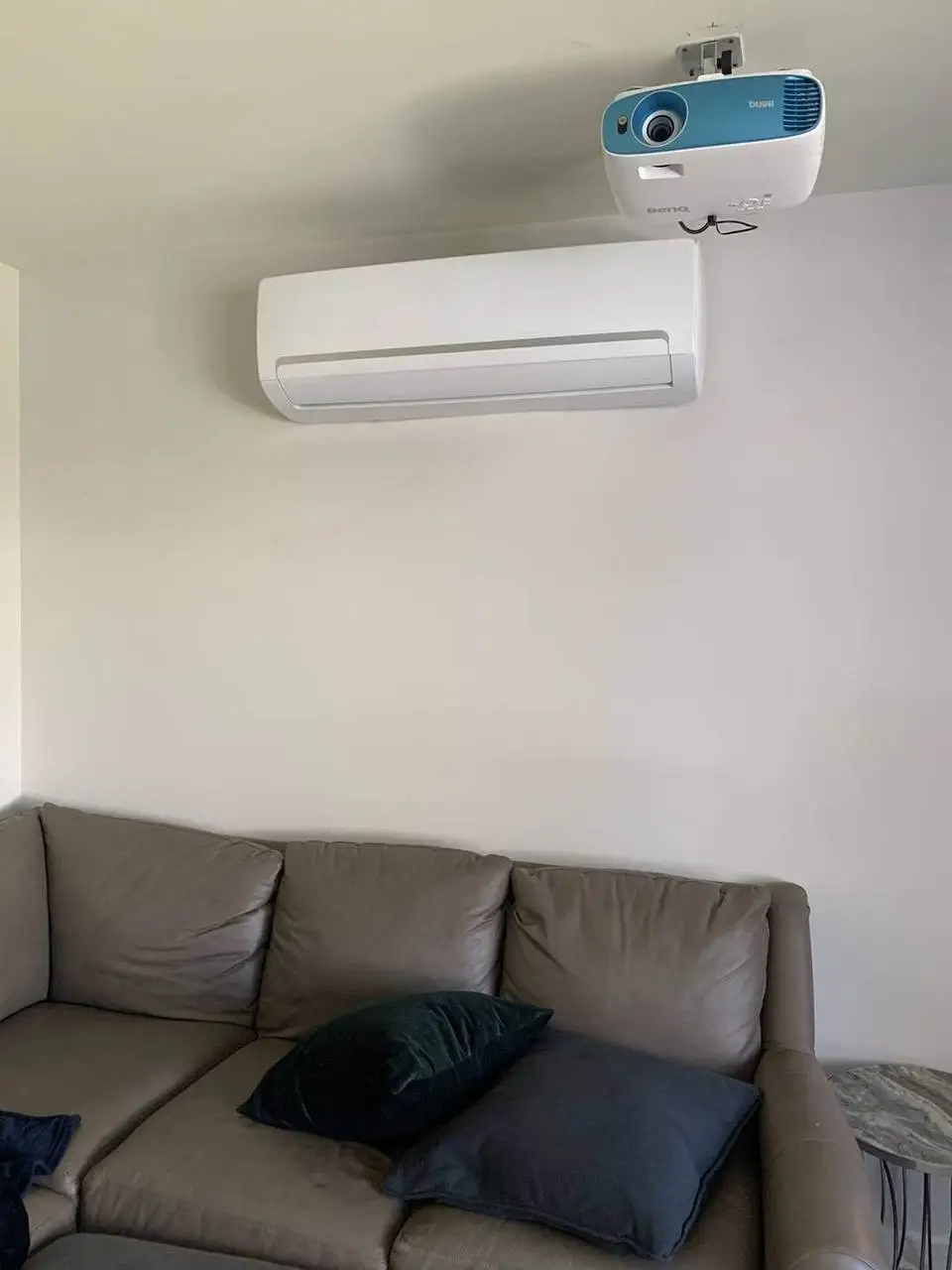Ductless mini-split wall unit above a living room sofa, installed by Electric A/C Inc