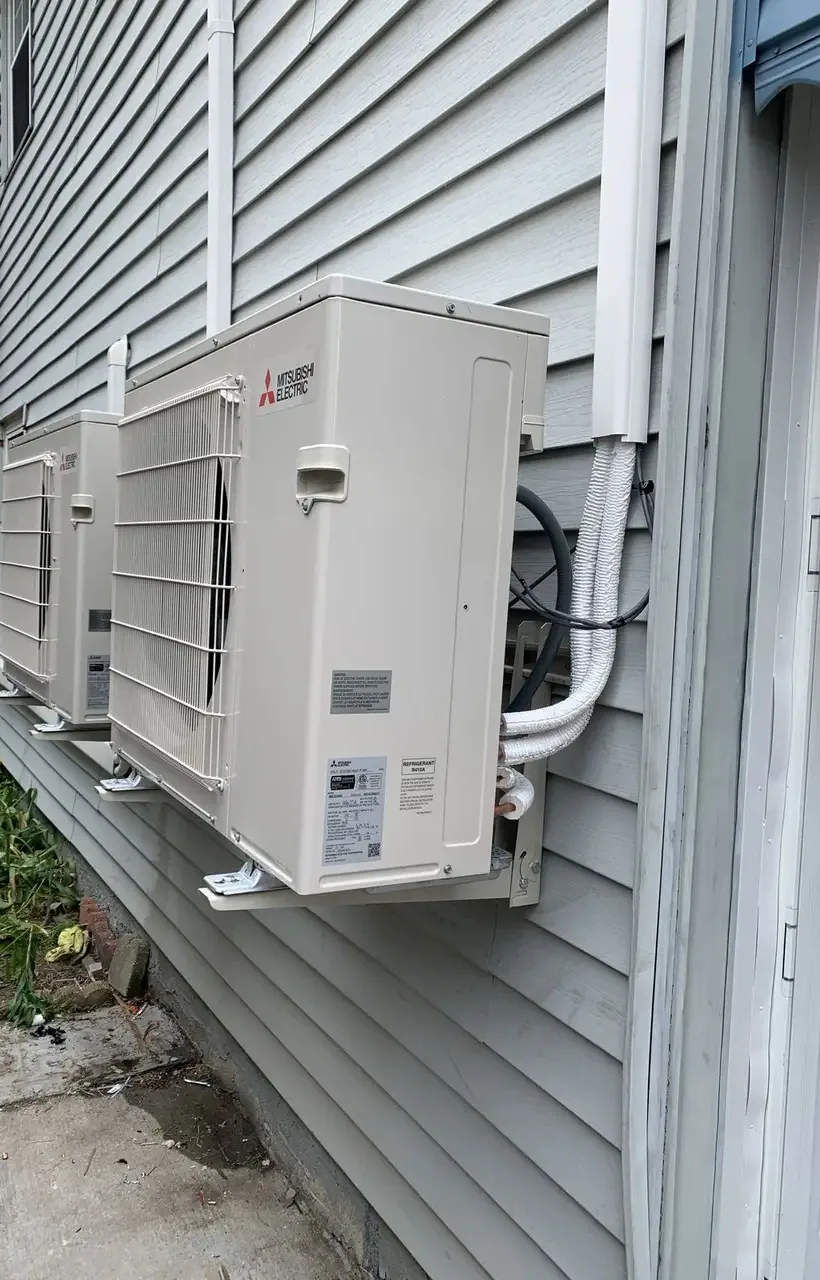 Pair of Mitsubishi ductless condensers on house siding, installed by Electric A/C Inc in Queens