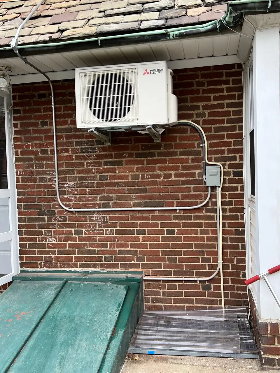 Mitsubishi condenser mounted on a brick wall by Electric A/C Inc